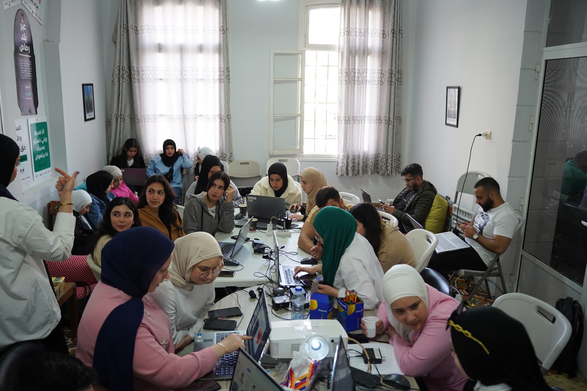 Young people working together on laptops around a table during a YARD training session in Tripoli.