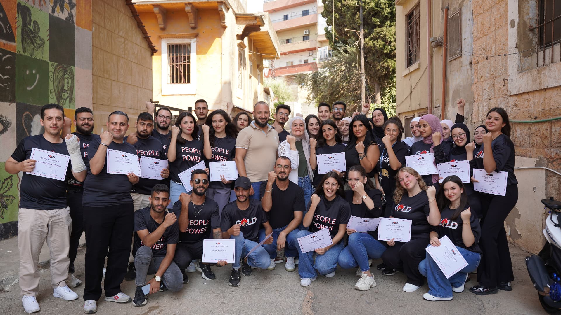 GOLD participants in Tripoli holding their certificates and raising their fists together.