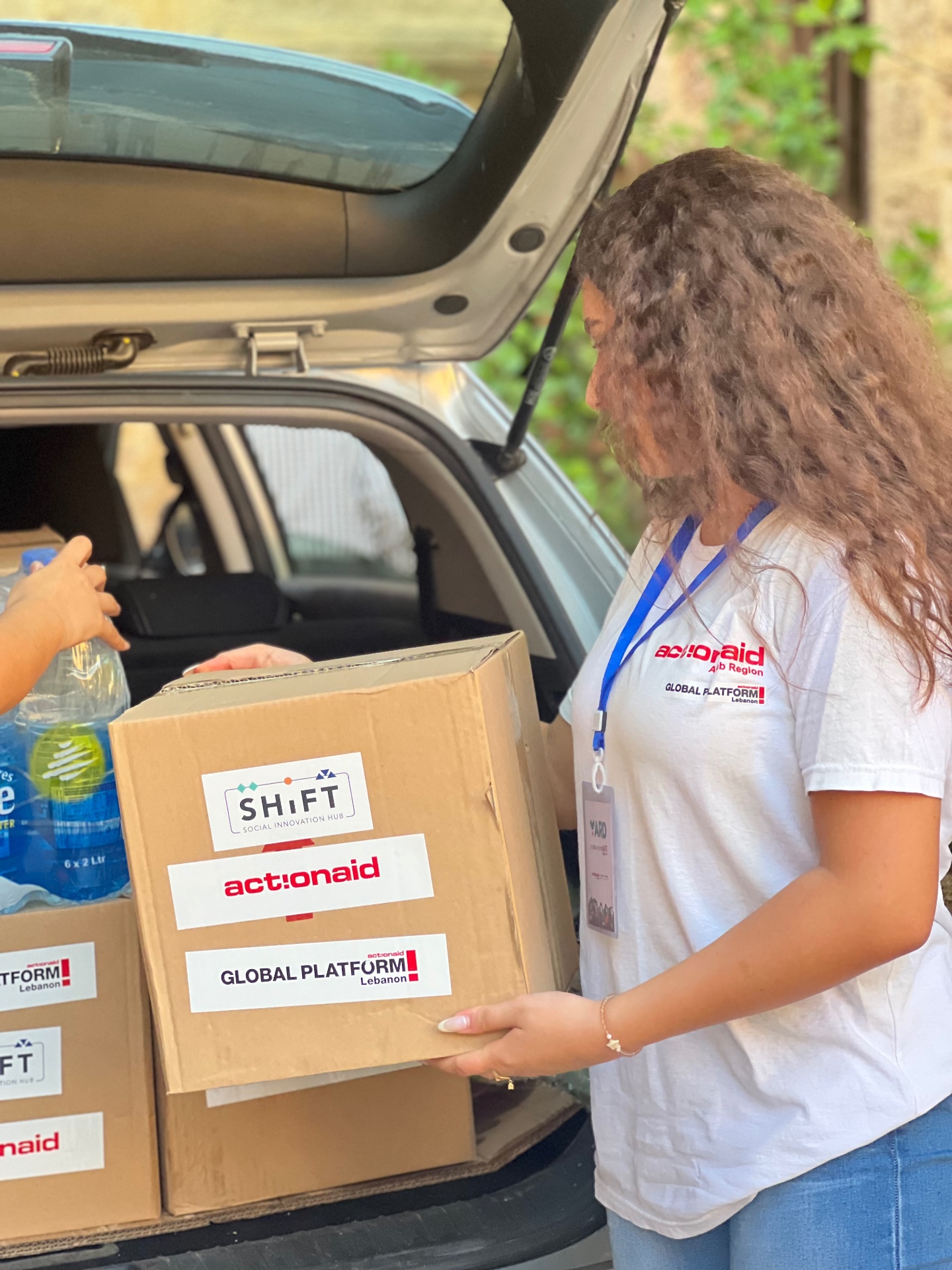 A YARD volunteer loading relief boxes of food and water into a car.